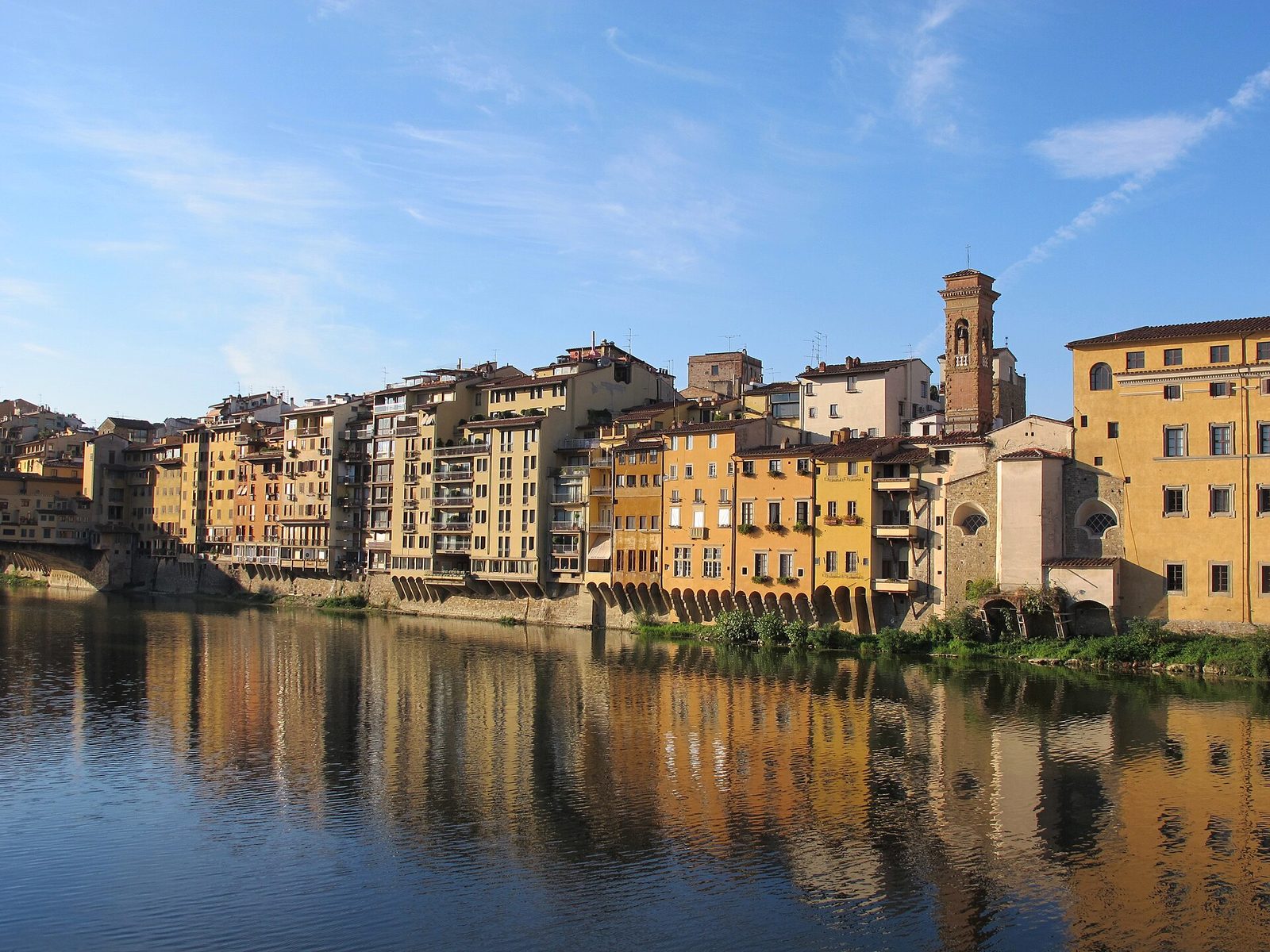 Le case color ocra di Borgo San Jacopo affacciate sull'Arno e riflesse nell'acqua, sotto un cielo azzurro